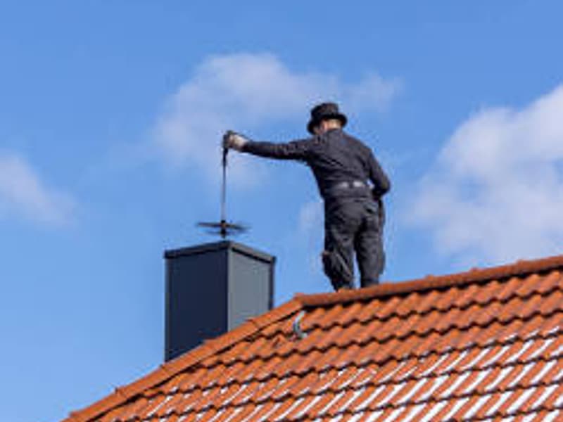 chimney sweep working at the flue from the roof on a chimney in Hamilton, NJ